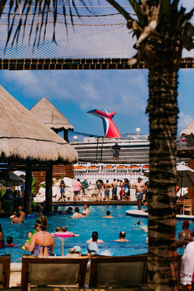 Crowd enjoying a sunny day at tropical resort near a cruise ship.